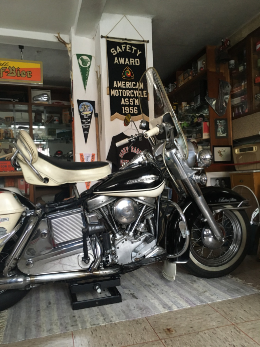 Electra Glide im Showroom, daneben Wimpel und die AMA-Sicherheitsurkunde von 1956